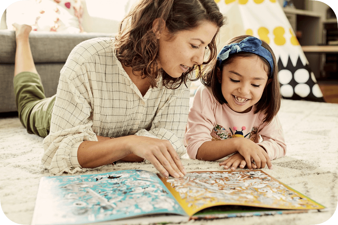 Smiling girl reading a book with her mother